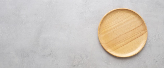 Empty round wooden plate on gray cement table background