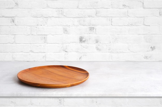 Empty round wooden plate on white cement table and wall background