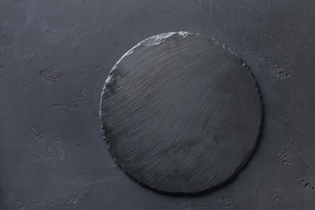 Photo empty rustic black slate stone plate on dark background, copy space, top view