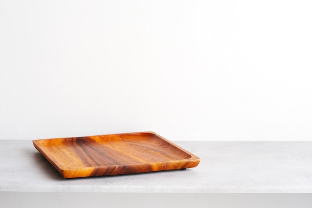 Empty rwooden plate on white cement table and cement wall background