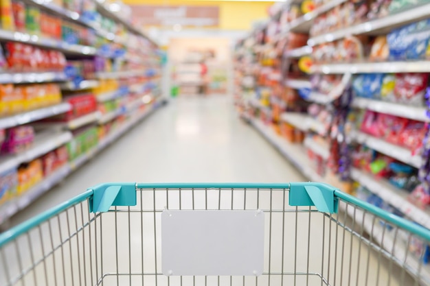 Empty shopping cart in department store with blurred background of shelves