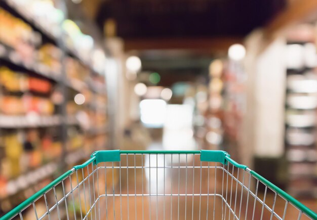 Empty shopping cart with abstract blur supermarket discount store aisle background