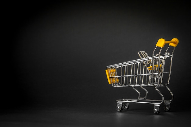 Empty shopping trolley on dark toned background with some copy space