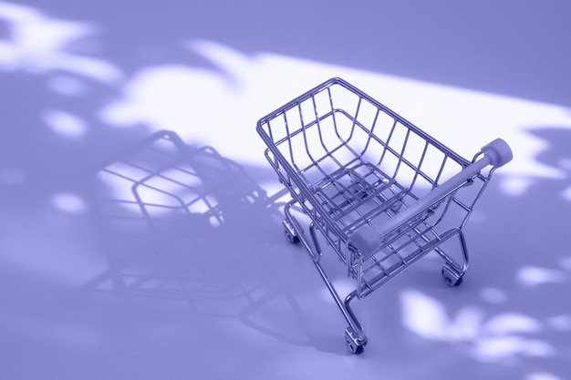 Empty small shopping cart with nature hard shadows toned very peri coloe