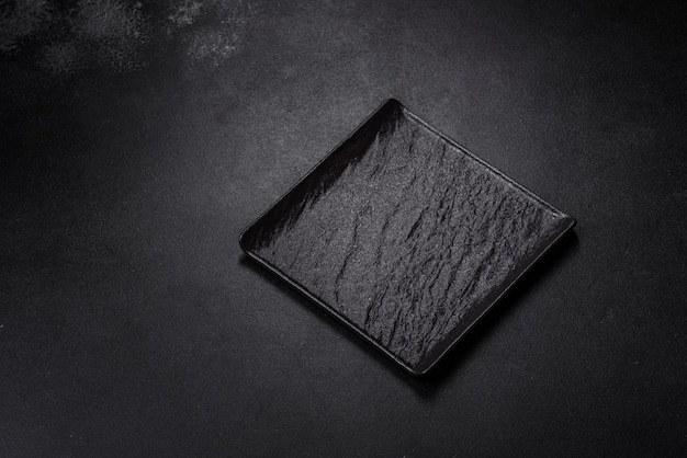 Empty square black plate on dark moody background with copy space