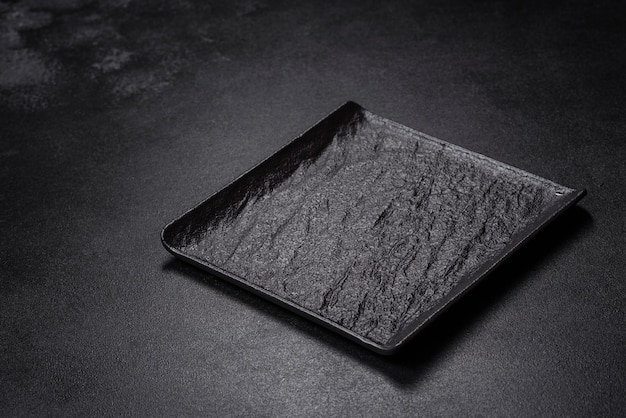 Empty square black plate on dark moody background with copy space