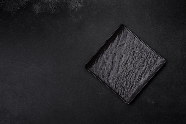 Photo empty square black plate on dark moody background with copy space