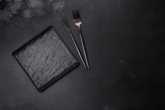 Empty square black plate on dark moody background with copy space