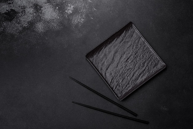 Empty square black plate on dark moody background with copy space