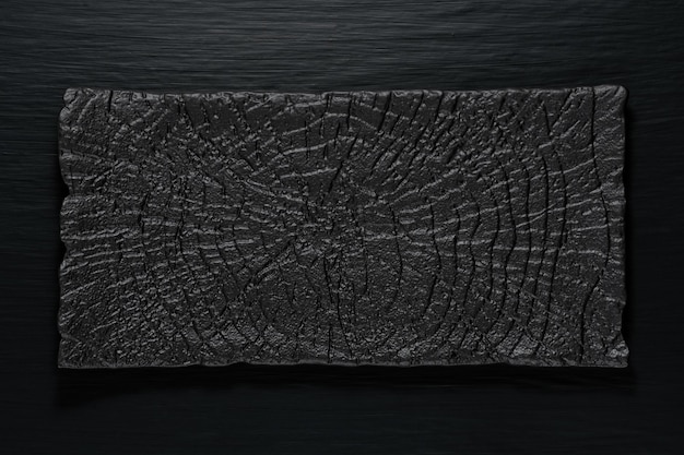 An empty square black plate on top of a rough wooden table Top view with copy space