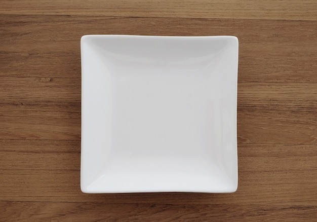 Empty square white plate in wood background