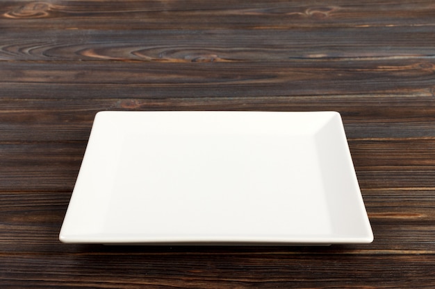 Empty square white plate in wood, food display montage. Perspective view