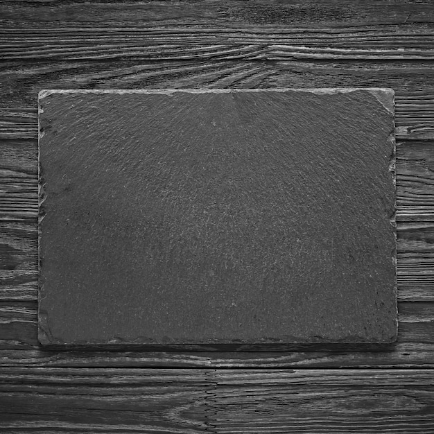 Photo empty stone cutting board on a wooden table. concept: kitchen, cooking, restaurant, menu