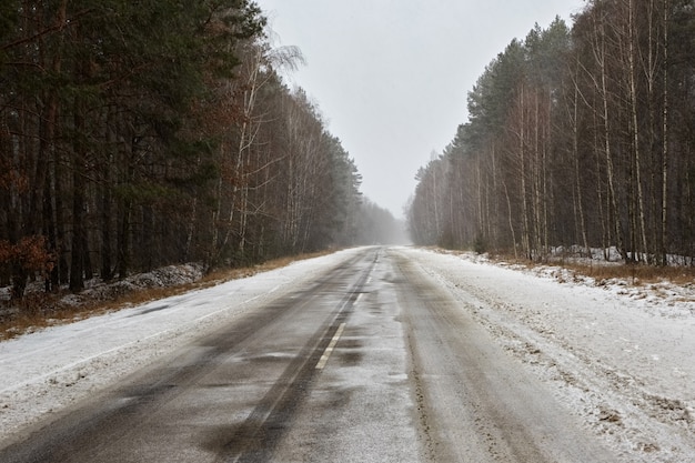 Photo empty straight highway in the snow through a pine forest