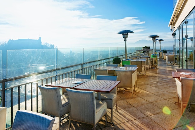 Empty street cafe with tables and chairs with beautiful panoramic background on old city of Ljubljana, morning capital of Slovenia. Modern restaurant design with lamps in sunny town, sunrise in winter