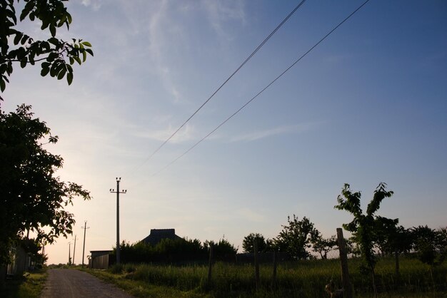 An empty street in the village electric wires and poles along the edge of the road a blue sky and