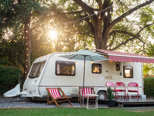 Empty sunbed beach seats and folding chairs with table in front of caravan car park in garden with nobody Relaxation nature camping and sleep in the motorhome trailer Family vacation travel concept