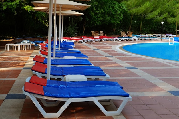 Empty sunbeds near swimming pool in luxury hotel