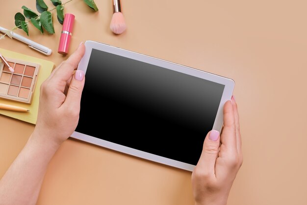 Empty tablet in woman's hands nexto beauty accessories