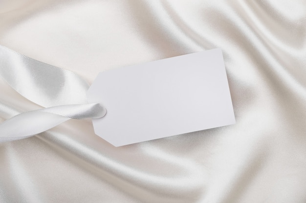 Empty tag card for text on white silk fabric. Mockup for design