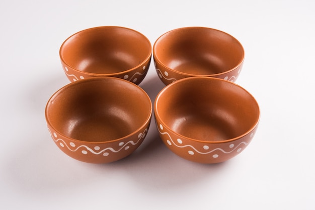 Empty terracotta dinnerware or dining set like plate, soup bowl, serving bowl, glass made up of brown clay, isolated over white