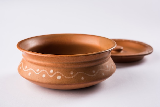 Empty terracotta dinnerware or dining set like plate, soup bowl, serving bowl, glass made up of brown clay, isolated over white