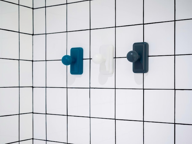 Empty three modern towel hooks blue and white hanging on white grid wall bathroom background with copy space minimal style