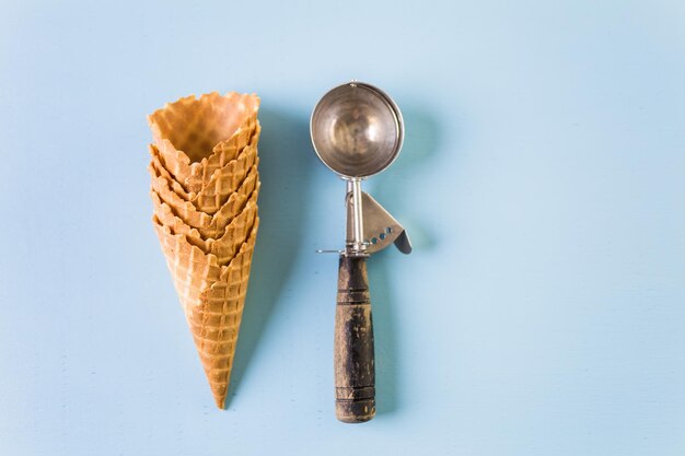 Empty waffle ice cream cones with ice cream scoop.