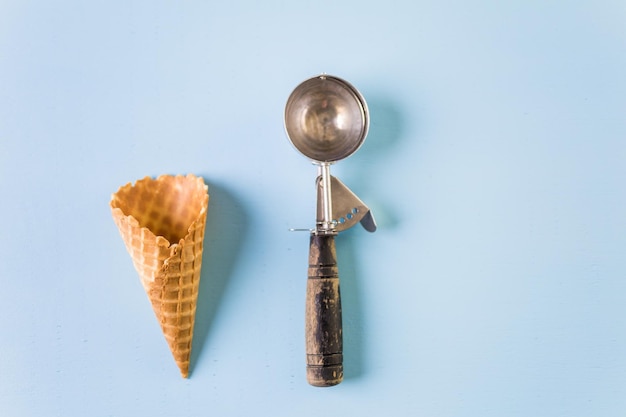 Empty waffle ice cream cones with ice cream scoop.