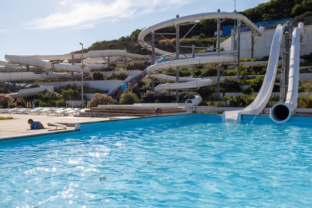 Empty water park with high white slides pools and white sun loungers