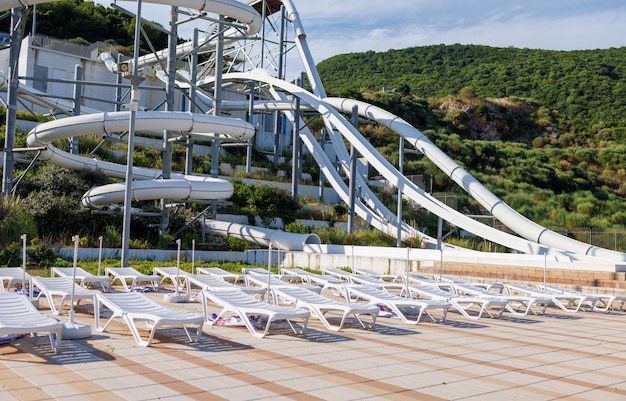 Empty water park with high white slides and white sun loungers