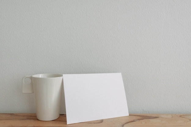 Empty white card mockup lean on a tea cup with white wall