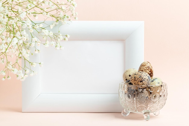 Empty white frame quail eggs in crystal bowl and white gypsophila on pastel pink Mock up