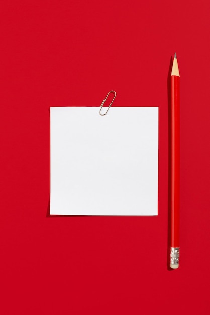 Photo empty white paper sheet for notes with red pencil on a red background