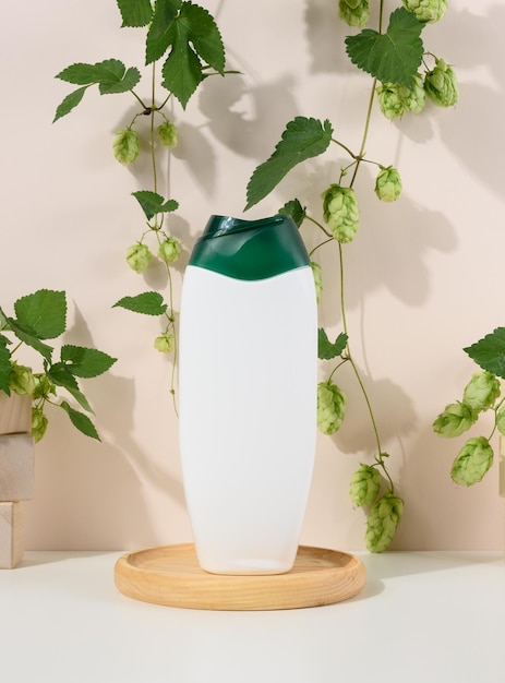 Empty white plastic bottle for gel shampoo and other liquid cosmetics on a beige background