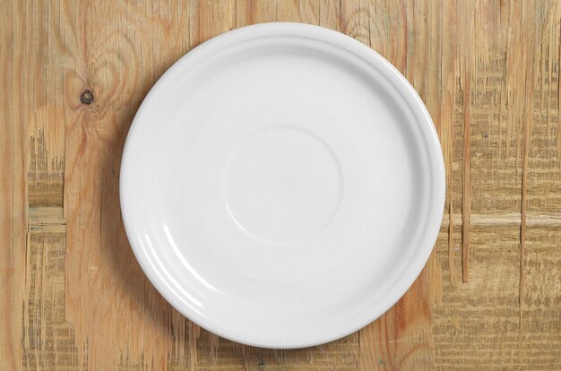 Empty white plate on old wooden background, top view