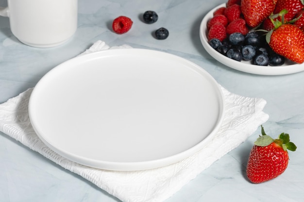 Empty white plate strawberries and blueberries on a light background