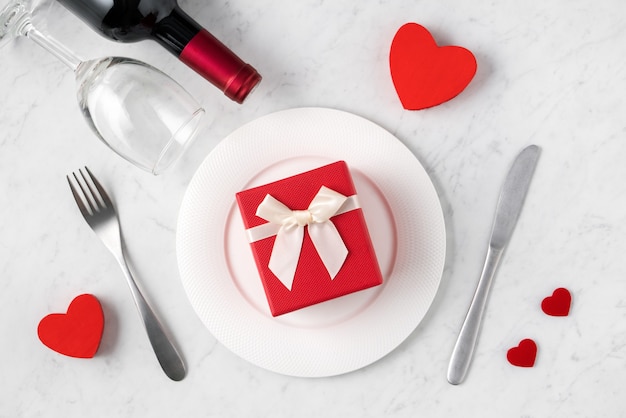 Empty white plate with tableware, ribbon, gift and roses for Valentine's Day