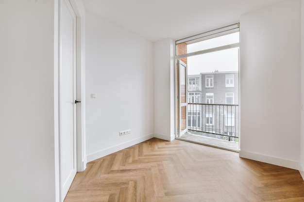 Empty white room with door leading to balcony