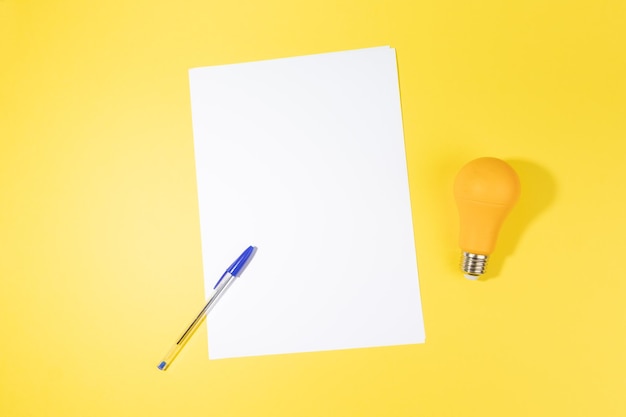 Empty a white sheet with pen and a bulb concept of writing creative ideas