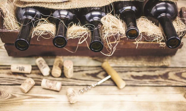 Empty wine bottles in a wooden box on a rustic table. 