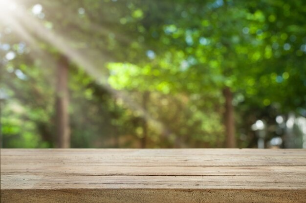 Empty of wood table top on blur of fresh green abstract from garden with sunlight .