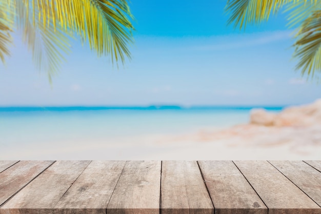 Empty wood table top and blurred Palm tree summer beach with blue sea and sky background.