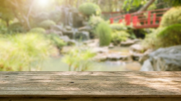 Empty wood table top with abstract blur park garden pond background