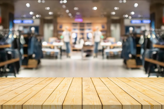 Empty wood table top with blur clothing boutique display interior shopping mall background