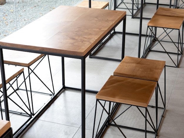 Empty wood of wooden table set with chairs on cement tiles background with no people loft style cafe interior Empty wood furniture with black steel bar decoration on concrete ground floor in cafe