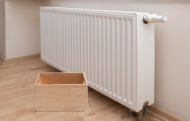 Empty wooden box and Modern white radiator with thermostat