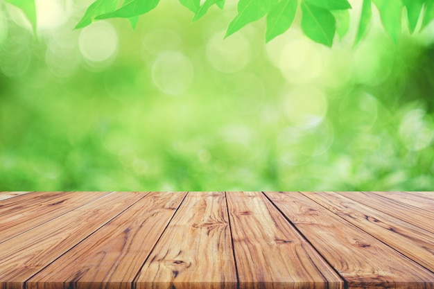 Empty wooden deck table top on green blurred abstract background from foliage background