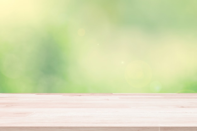 Empty wooden deck table top on green blurred abstract background.