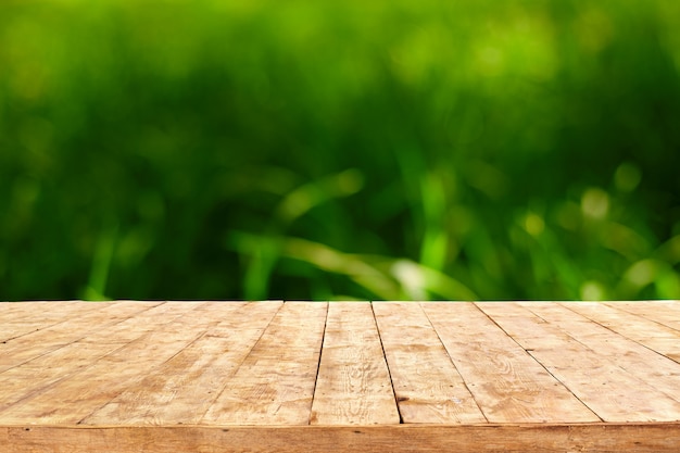 Empty wooden deck table with foliage bokeh background. Ready for product display montage.